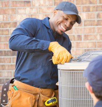 A smiling technician repairing an air conditioner in Imlay City.